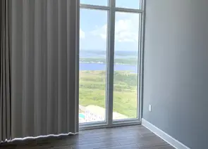 Modern vertical drapery curtains installed on tall floor to ceiling condo windows overlooking the Alabama coast - Beach Blinds window treatments
