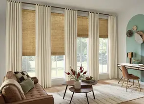 Natural woven wood shades layered with elegant drapery panels in stylish living room of Alabama home - Beach Blinds window coverings
