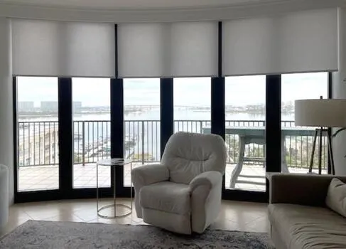 Light filtering solar roller shades on large curved condo windows overlooking the coast in Alabama - Beach Blinds window coverings