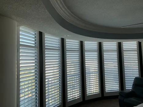 Custom white plantation shutters installed on large curved floor to ceiling condo windows in Alabama - Beach Blinds window treatments