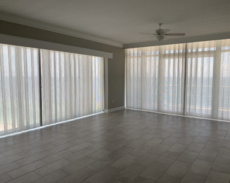 Elegant sheer drapery curtains installed on large sliding glass doors and tall windows in Alabama home - Beach Blinds window treatments
